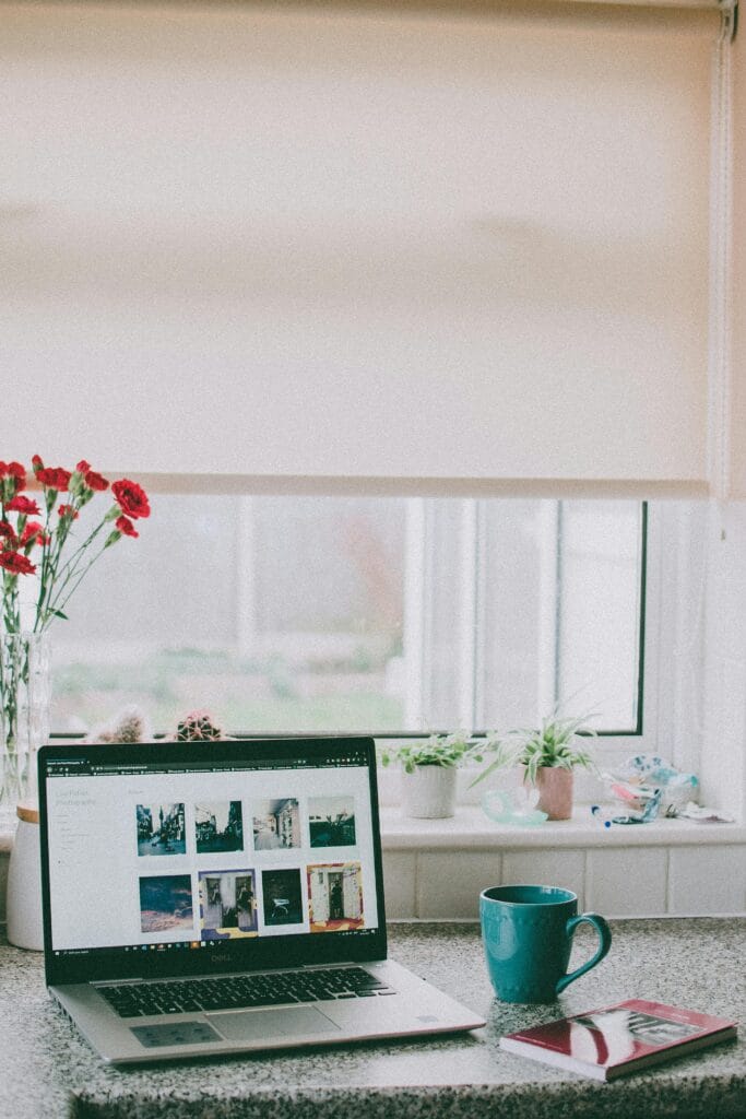 pexels-photo-3716515-3716515 A cozy home office setup with a laptop, coffee mug, and flowers by a sunlit window, ideal for remote work.
